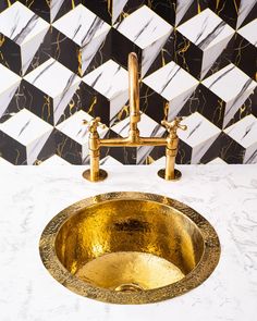 a gold sink in front of a black and white tiled wall