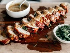 sliced meat with sauce and herbs on a cutting board