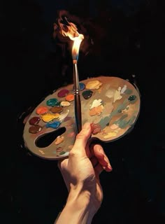 a person holding a paint palette with a candle on it