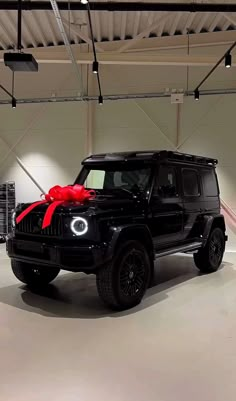 a black jeep with a red bow on it's hood