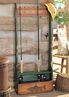 an old wooden box with fishing rods in it sitting next to a log cabin wall