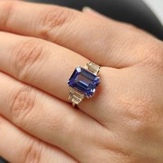 ITEM DESCRIPTION: >> The Ring is made from Solid 14K Yellow Gold. Gemstone used is absolutely natural and ethically sourced. >> Natural Tanzanite in Emerald Cut and octagon & Baguette shape is studded on it with utmost precision. >> This is a minimalist design which makes it a hassle free and everyday jewelry. Gem: Tanzanite Gem size: 10x8mm Gem Weight: 3.424 carats and octagon shape Gem: White Topaz Gem size: 5×2.5, 4×2 mm and Baguette Gem Weight: 0.826 carats Gold purity: 14K (58.33% approx.) Rings With Tanzanite, Tanzanite Ring Engagement, Classic Tanzanite Ring With Center Stone, Tanzanite Rings, Emerald Cut Tanzanite Ring, Gold Tanzanite Wedding Birthstone Ring, Tanzanite Topaz Gemstone Ring As Gift, Gold Tanzanite Gemstone Rings, Gold Tanzanite Birthstone Ring