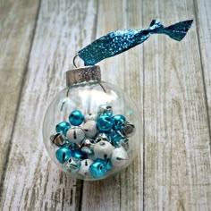 a glass ornament filled with blue and white ornaments on top of a wooden table