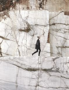 a man walking across a stone wall with mountains in the background