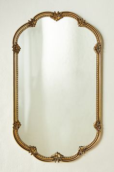 an ornate gold framed mirror hanging on the wall