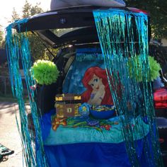 the trunk of a car decorated with blue streamers and ariel the little mermaid decorations