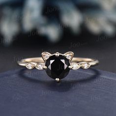 a black and white diamond ring sitting on top of a blue cloth with diamonds around it