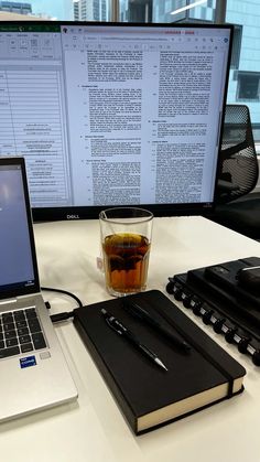 an open laptop computer sitting on top of a desk next to a cup of tea