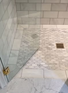 a shower with a glass door and tiled floor