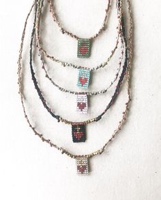 four beaded necklaces are arranged on a white surface