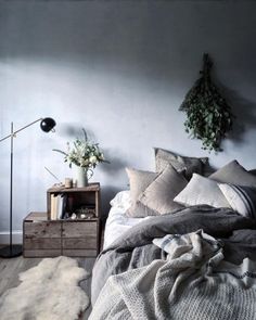 an unmade bed with pillows and blankets in a bedroom next to a lamp on a table