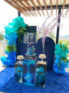 a table topped with blue balloons and cake