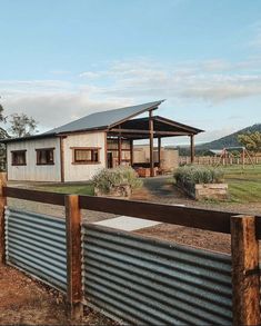 a house with a metal fence in front of it and a grassy field behind it