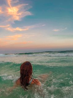 a woman swimming in the ocean with her back turned to the camera and looking at the sky