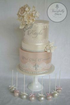 a three tiered wedding cake with flowers and pearls on the top is surrounded by small pins