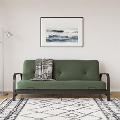 a green couch sitting on top of a wooden floor next to a white and black rug