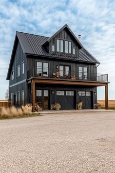 a large black house sitting on top of a gravel road