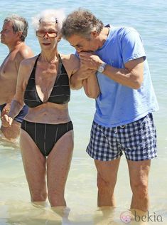 an older man and woman standing in the water