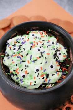 a black bowl filled with green frosting and sprinkles