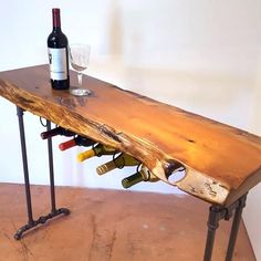 a wooden table with wine bottles and glasses on it, sitting next to a wall