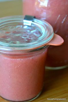 two jars filled with pink liquid sitting on top of a wooden table