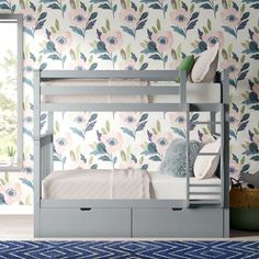 a white bunk bed sitting in front of a window next to a wall with flowers on it