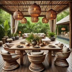 an outdoor dining area with wicker chairs and wooden table surrounded by hanging lights above it