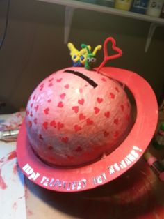 a pink hat with hearts on it sitting on top of a table