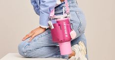 a woman sitting on top of a white table holding a pink cup