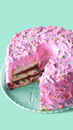 a cake with pink frosting and sprinkles on a green platter