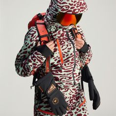 a person wearing skis and carrying a snowboard on their back with an animal print jacket