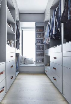 a walk in closet with white cabinets and drawers