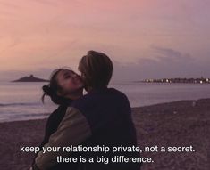 a man and woman kissing on the beach at sunset with an ocean in the background