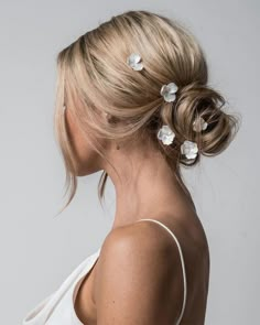 a woman with blonde hair wearing a white dress and two flower clips in her hair