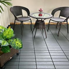 three chairs and a table on a tile floor in front of a potted plant