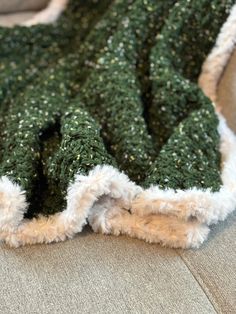 a blanket covered in green and white speckles sitting on top of a couch