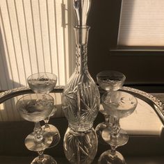 an assortment of wine glasses and a decanter sitting on a table in front of a window