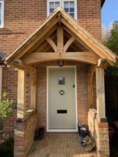 a white front door sitting next to a tall brick building with a wooden frame on it's side