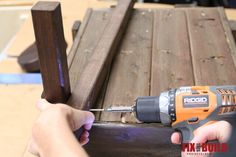 a person using a drill to attach a wooden bench