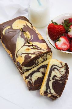 a chocolate covered cake next to a bowl of strawberries