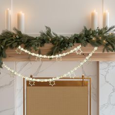 a decorated mantle with candles and garland on it