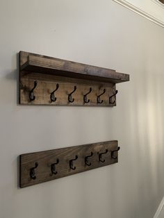 two wooden shelfs with hooks on them are mounted to the wall in a hallway