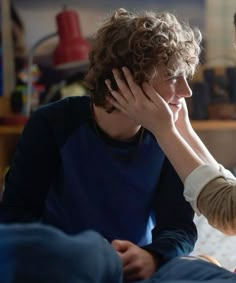 a woman talking to a child who is sitting on a bed with her head in her hands