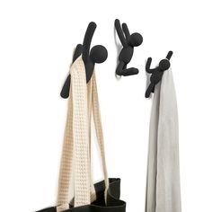 a pair of black and white hooks on the wall next to a bag with two coats hanging from it