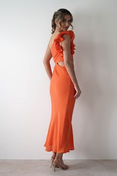 a woman in an orange dress poses for the camera with her hands on her hips