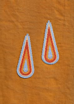 two small beaded earrings sitting on top of a piece of cloth