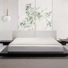 a white bed sitting in a bedroom next to a window with bamboo blinds on it