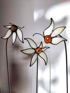 three stained glass flowers are sitting on top of each other in front of a white wall