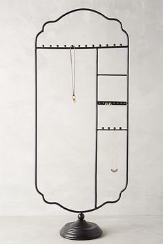 a black metal jewelry rack with two necklaces hanging from it's sides, on a white background