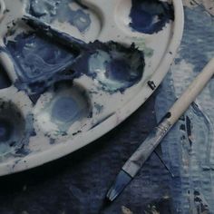 a paint palette and brush sitting on top of a dirty plate with watercolors